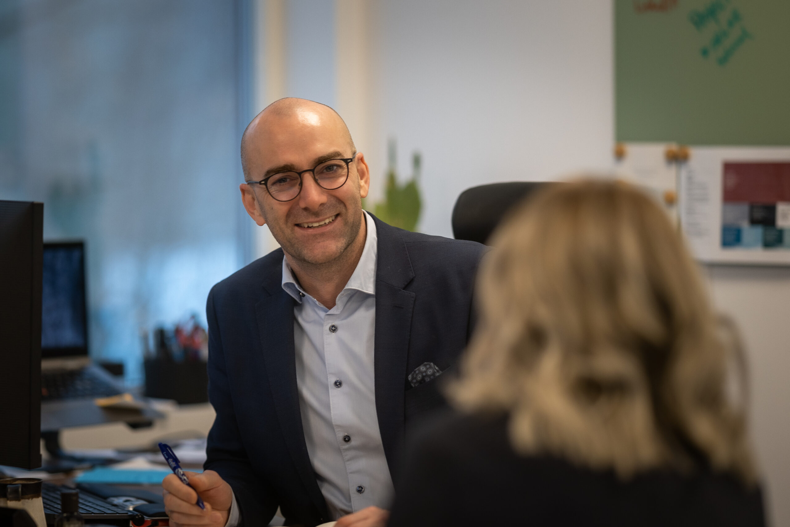 Arnt smiler mot kamera ved skrivepult